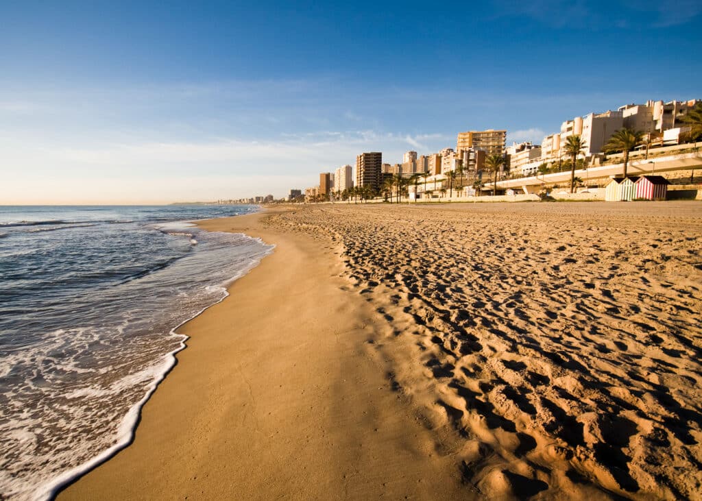 Het zacht kabbelend water van het strand met op de achtergrond de boulevard van El Campello.